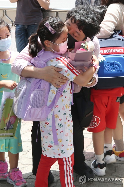 "첫 등교 축하해" 꽃다발 건네는 아빠(광주=연합뉴스) 천정인 기자 = 유치원과 초등학교 1~2학년이 첫 등교를 한 27일 광주 서구 치평초등학교에서 한 학부모가 첫 등교를 축하하는 꽃다발과 인형 선물을 자녀에게 전하고 있다. 2020.5.27 iny@yna.co.kr