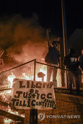 USA MINNESOTA GEORGE FLOYD DEATH PROTESTepa08451219 Protesters cheer as fire burns outside a Minneapolis police precinct during protests over the arrest of George Floyd, who later died in police custody, in Minneapolis, Minnesota, USA, 28 May 2020. A bystander's video posted online on 25 May, appeared to show George Floyd, 46, pleading with arresting officers that he couldn't breathe as an officer knelt on his neck. The unarmed black man later died in police custody.  EPA/CRAIG LASSIG