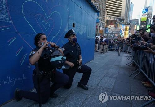 미국 뉴욕경찰(NYPD) 소속 경찰관들이 31일(현지시간) 타임스퀘어에서 시위대 앞에 무릎을 꿇고 연대의 뜻을 표하고 있다. 시위는 지난달 25일 미네소타주 미니애폴리스에서 흑인 조지 플로이드가 백인 경찰한테 목을 짓눌려 사망한 사건에 항의하고자 열렸다. [AFP=연합뉴스 자료사진]