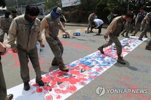 STX조선해양 무급휴직 연장 반대(창원=연합뉴스) 우정식 기자 = 1일 경남 창원시 STX 조선해양 정문에서 열린 집회가 끝나고 노조원들이 '구조조정, 무급휴직'이 인쇄된 플래카드에 페인트를 작업화로 밟는 퍼포먼스를 하며 작업장으로 들어가고 있다. 2020.6.1 uhcho@yna.co.kr