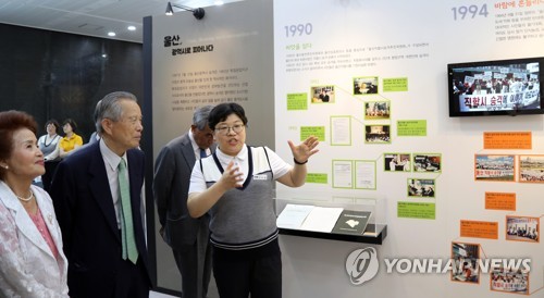 광역시 승격 20주년 '성년 울산' 특별전2017년 7월 울산시청에서 광역시 승격 20주년을 맞아 성년 울산 특별기록전이 열리고 있다. 심완구(왼쪽에서 두번째) 전 울산시장과 성주향(맨 왼쪽) 부부상담소장이 해설자의 설명을 듣고 있다. 
[연합뉴스 자료사진]