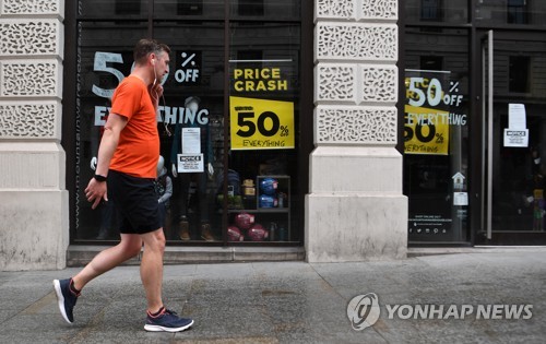 세일 표지가 붙어있는 상점 앞을 지나가는 런던 시민 [EPA=연합뉴스]