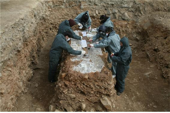 2010년 쪽샘 C-10호 고분의 말갑옷 출토 부위의 토층을 떠서 옮기기에 앞서 사전 작업으로 표면에 한지를 씌우고 방수약재를 뿌리고 있는 모습이다.