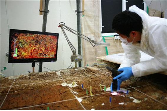 통째로 떠서 국립경주문화재연구소로 옮겨진 말갑옷 출토 부분의 토층과 유물을 연구진이 디지털전자현미경으로 분석하고 있다.