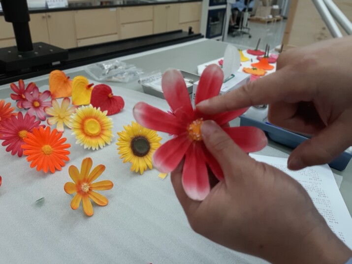 청주관 조각실 수복 작업대 위에 놓인 최정화 작가의 조형물 <플라워트리>의 꽃잎 장식물들. 한 연구원이 꽃잎 하나를 들어 부서진 부위를 가리키고 있다.