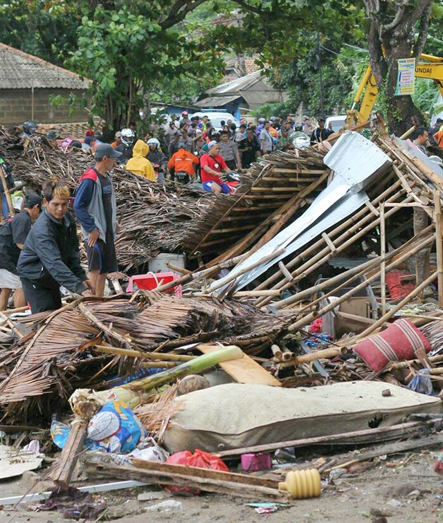 인도네시아 카리타에서 23일 주민들이 전날 밤 발생한 쓰나미에 휩쓸려 처참히 부서진 가옥의 잔해더미를 망연자실한 표정으로 바라보고 있다. 카리타=AP 연합뉴스