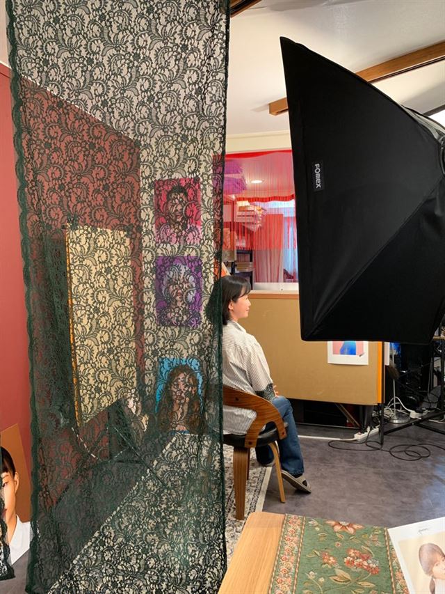 임미선씨가 검은색 망사천이 드리워진 공간 뒤에서 베이지색을 배경으로 증명사진을 찍고 있다.