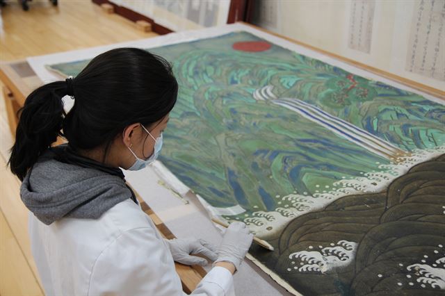 15일 대전 유성구 문화재보존과학센터 지류문화재보존실의 관계자가 서울 창덕궁 인정전 어좌 뒤에 걸렸던 '일월오악도'를 보존 처리 하고 있다. 건식 세척 단계다. 신지후 기자