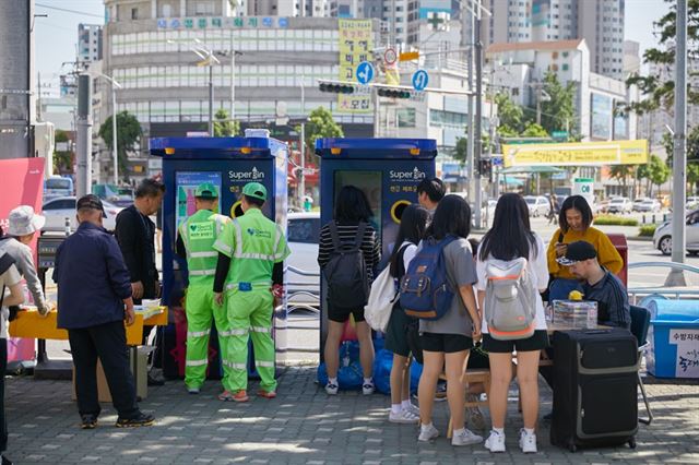 시민들이 서울 동대문구 전농동에 설치된 수퍼빈의 순환자원 회수로봇 '네프론'에 페트병과 캔 등을 투입하고 수거 개수만큼 포인트를 적립하고 있다. 수퍼빈 제공