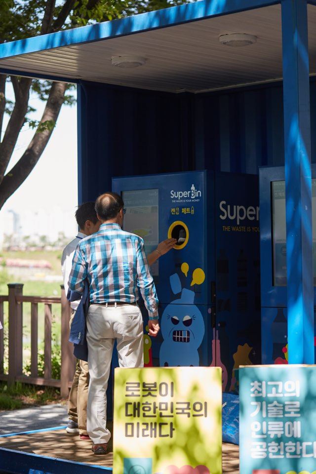 시민들이 서울 동대문구 벚꽃길에 설치된 자원순환 로봇 '네프론'에 캔과 페트병을 넣고 포인트를 적립하고 있다. 수퍼빈 제공