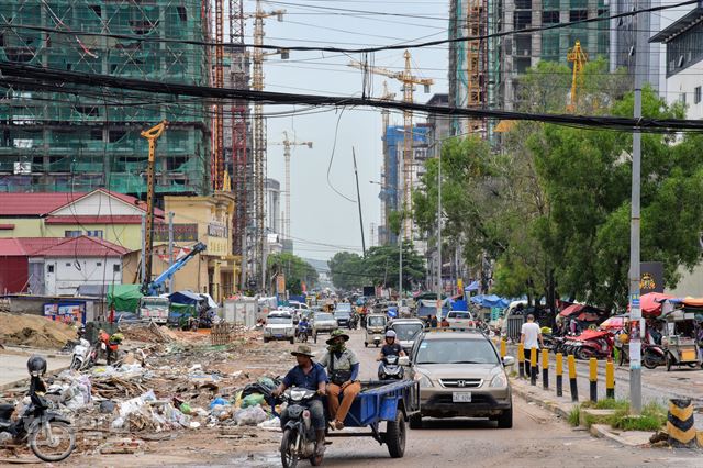 시아누크빌 시내 풍경. 중국 자본에 의한 호텔, 카지노, 아파트 공사가 한창이다. 공사장에서 나온 쓰레기, 움푹 패인 도로의 물을 피해 자동차와 오토바이들이 위태롭게 달리고 있다.