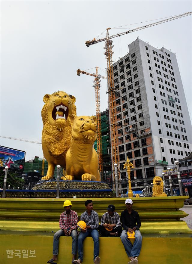 캄보디아 최대 항구도시인 시아누크빌 중심지에 있는 황금 사자상 앞에서 공사현장 근로자들이 휴식을 취하고 있다. 사자상 뒤로 중국 자본들이 올리고 있는 건축물 공사가 한창이다. 사자상 회전교차로(육거리)에는 어느 방향을 바라봐도 공사장들뿐이다. 시아누크빌=정민승 특파원