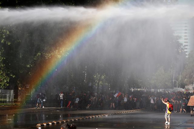 0칠레 정부가 지하철 요금 50원 인상으로 촉발한 반정부 시위가 격화되면서 오는 16일~17일 열릴 예정이었던 아시아태평양경제협력체(APEC) 정상회의와 12월 유엔 기후변화협약 당사국총회(COP25)를 취소했으나 반정부 시위는 계속 되고 있는 가운데 31일(현지시간) 산티아고의 모네다 궁전 앞에서 시위대 해산을 위해 진압경찰이 쏘는 물대포를 맞고 있는 시위대 앞에 무지개가 떠 있다. EPA 연합뉴스