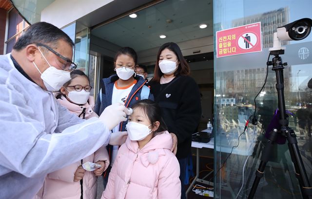 23일 오전 서울 영등포구 여의도순복음교회 제2교육관 입구에서 주일학교에 참석한 가족들을 상대로 교회 관계자가 체온 측정을 하고 있다. 연합뉴스