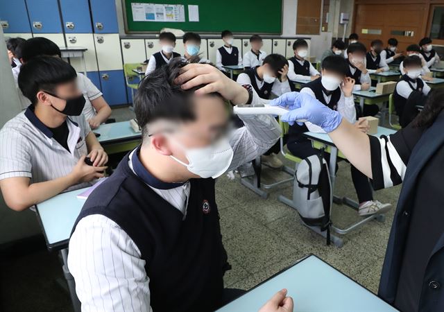 고교 3학년 등교 개학이 시작된 20일 오전 경기 수원시 팔달구 수원고에서 교사가 학생들 체온 측정을 하고 있다. 연합뉴스