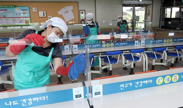 고2·중3·초1∼2·유치원생의 등교 수업 재개를 하루 앞둔 26일 강원 춘천시 금병초등학교 급식실에서 조리원들이 식탁 가림막을 소독하고 있다. 춘천=연합뉴스