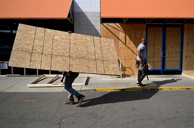 미국 워싱턴에서 2일 흑인 사망에 항의하는 야간 시위를 앞두고 과격시위로부터 유니언 마켓을 보호하기 위한 작업 중인 직원들이 판자를 옮기고 있다. 워싱턴=로이터 연합뉴스