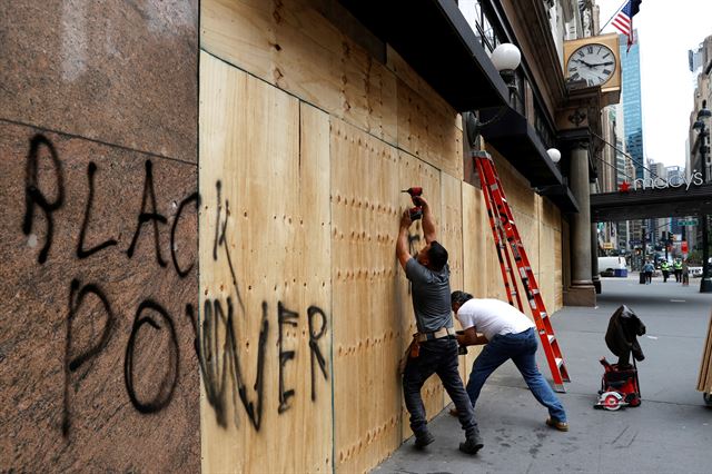 미 뉴욕 맨해튼의 메이시스 백화점 해럴드 스퀘어점이 조지 플로이드 사망 항의 시위 중 약탈을 받은 가운데 2일 직원들이 시위대로부터 매장을 보호하기 위해 판자를 덧대는 작업을 하고 있다.  뉴욕=로이터 연합뉴스