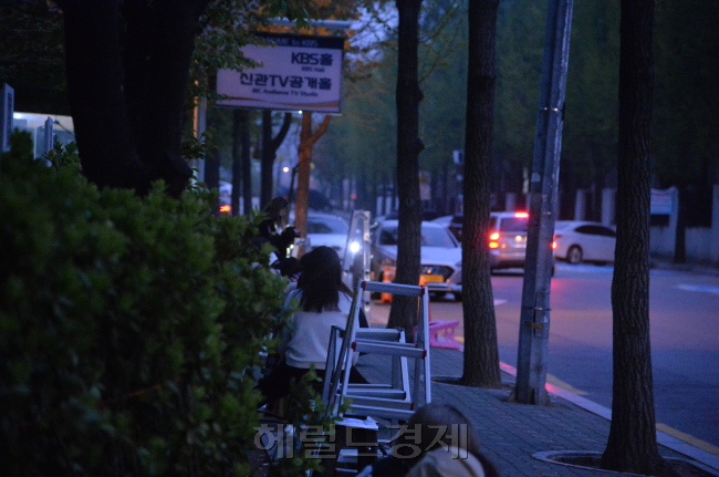 [18일 오후 7시께. 서울 여의도 KBS 방송국 앞에서 아이돌 출근길 촬영을 위해 줄지어 늘어선 ‘홈마’들의 모습. 저마다 대포 카메라로 불리는 고가의 촬영장비를 들고 있다. 이들이 기다리는 아이돌의 출근길은 다음달 아침 7시가 돼야 시작된다. 김유진 기자/kacew@heraldcorp.com]