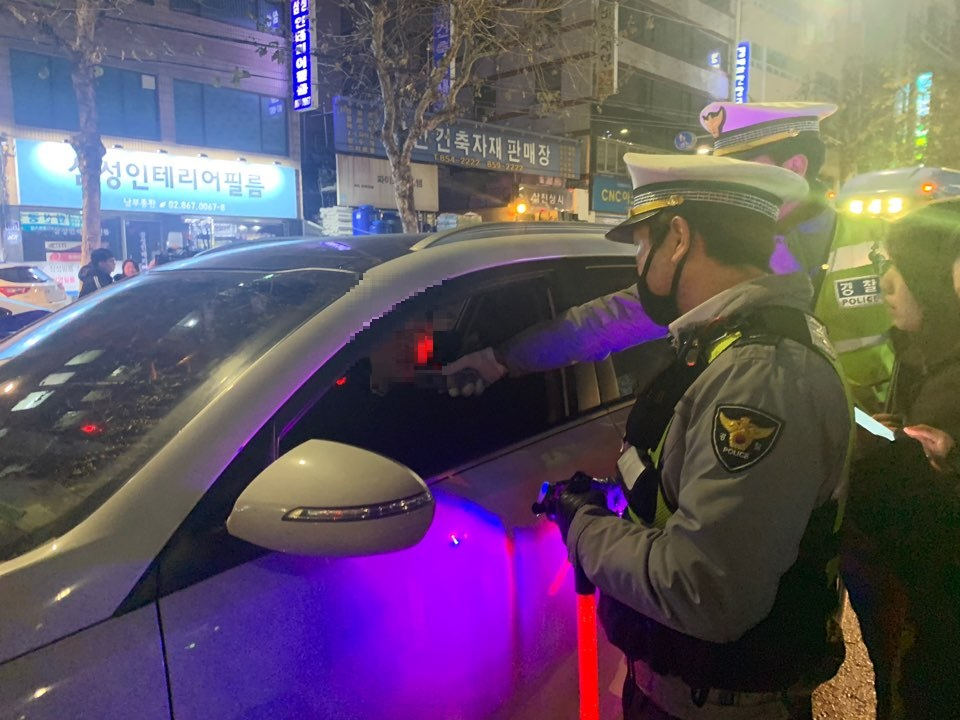 2019년 12월 16일 오후 10시 29분 이날 단속 시작 6분 만에 처음으로 적발된 A씨가 음주 감지기에 입김을 불고 있다. 이날 A씨의 혈중 알코올 농도는 0.037로 면허 정지 수준이지만, 기존 음주운전 전과 2개가 있던 A씨는 면허 취소 처분을 받았다. [사진=박상현 기자]