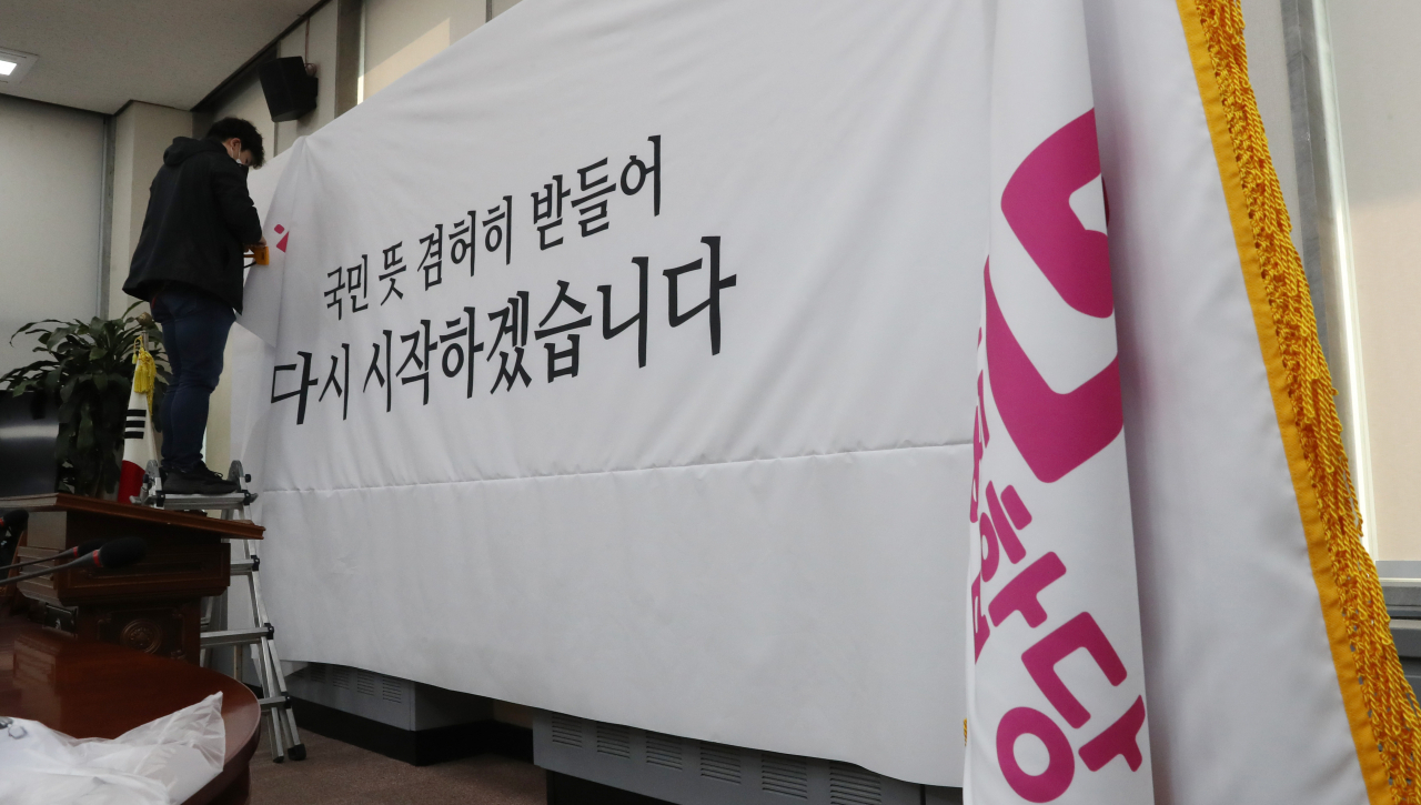 16일 오전 미래통합당 김종인 총괄선대위원장의 총선 결과 관련 특별기자회견이 열릴 서울 여의도 국회 미래통합당 회의실에서 관계자가 “국민 뜻 겸허히 받들어 다시 시작하겠습니다” 글귀가 쓰인 배경현수막을 설치하고 있다. [연합]