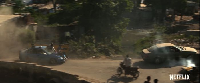 익스트랙션 촬영팀이 달리는 자동차 보닛에 앉아 앞서 가는 배우들의 액션 차량을 찍고 있다.