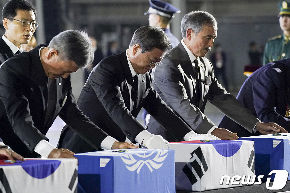 문재인 대통령이 25일 경기 성남 서울공항에서 열린 6.25전쟁 70주년 행사에 참석해 국군 전사자들의 유해함에 참전기장을 수여하고 있다. 왼쪽부터 박삼득 국가보훈처장, 문 대통령, 해리 해리스 주한미국대사.(청와대 제공)2020.6.26/뉴스1