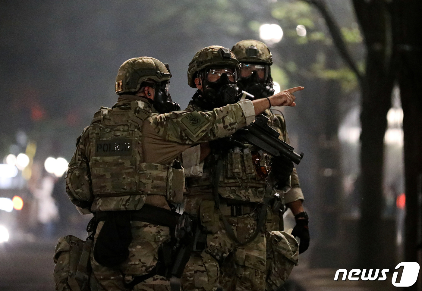 미국 오리건주 포틀랜드에서 신원미상의 연방 법 집행기관 요원들이19일(현지시간) 최루탄을 쏘기 전에 시위대를 손가락으로 가리키고 있다. © 로이터=뉴스1