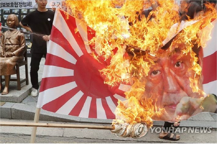 한국대학생진보연합 학생들이 지난 7월 29일 오후 서울 종로구 옛 주한일본대사관 앞 소녀상에서 일본의 강제징용 사죄 촉구 및 전범 기업 규탄 기자회견을 하던 중 욱일기와 아베 총리 사진을 불태우고 있다. (사진제공=연합뉴스)