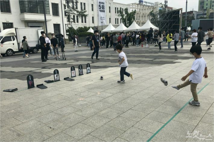 16일 아이들이 5·18왜곡·폄훼하는 사람들의 얼굴을 붙인 표지석에 신발을 날려 맞추는 게임을 하고 있다. (사진=김한영 기자)