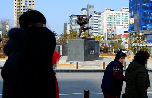 안중근 의사 동상 앞으로 많은 시민이 지나다니고 있다.