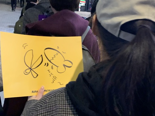 한 회원이 남성 성기를 가위로 자르는 그림을 들고 시위 구호를 외치고 있다.