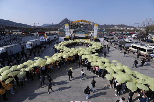세월호 참사 5주기를 사흘 앞둔 13일 오후 서울 종로구 광화문 광장에서 노란 우산으로 세월호 리본을 형상화하는 플래시몹이 펼쳐지고 있다. 연합뉴스