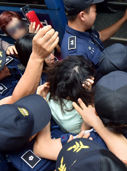 12일 오전 제주지법에서 전 남편을 잔혹하게 살해한 뒤 시신을 훼손·유기한 혐의를 받는 고유정(36)의 첫 공판이 열린 가운데 시민들이 호송차에 오르는 고유정의 머리채를 잡아 당기자 고씨가 얼굴을 감싸고 있다. 뉴시스