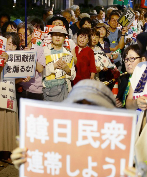 지난 19일 오후 도쿄 나가다초 국회의사당 인근에서 열린 아베 정권 규탄 집회에서 한 참가자가 '한일민중 연대하자'라고 적힌 손팻말을 들어 보이고 있다. 도쿄=연합뉴스