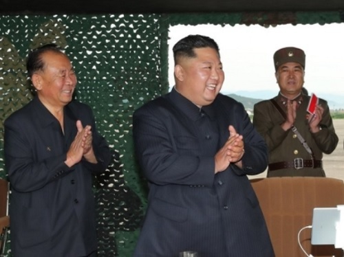 북한 김정은 국무위원장(가운데)이 한국을 겨냥한 신형 미사일 발사 실험에 성공한 뒤 활짝 웃으며 손뼉을 치고 있다. 연합뉴스