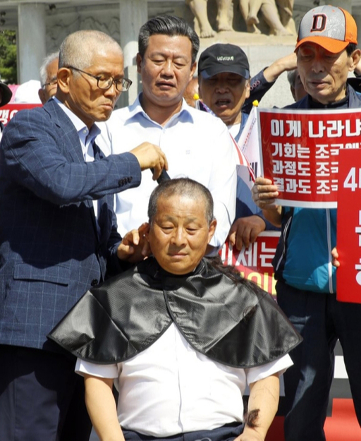 자유한국당의 조국 법무부 장관 사퇴 촉구 '릴레이 삭발 투쟁'에 중진 의원들이 합류하고 있는 지난 18일 오전 청와대 앞 분수대 광장에서 차명진 전 의원이 동참하고 있다. 전날 삭발한 김문수 전 경기도지사가 직접 차 전 의원의 머리카락을 잘라주고 있다. 연합뉴스