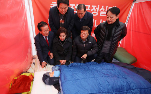 단식 8일차를 맞은 자유한국당 황교안 대표가 27일 청와대 앞 분수대 광장 천막을 찾은 나경원 원내대표 등 한국당 의원들을 누운 채 만나고 있다. 연합뉴스