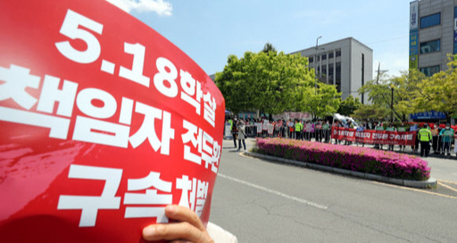 전두환 전 대통령이 사자명예훼손 사건 재판과 관련해 27일 광주지방법원으로 들어가자 광주지역 시민단체 회원들이 법원 입구에서 피켓을 들고 시위를 하고 있다. 연합뉴스