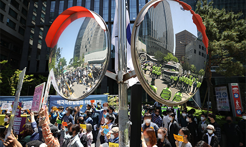 13일 서울 종로구 옛 일본대사관 앞에서 열린 일본군 위안부 문제 해결을 촉구하는 수요시위(왼쪽)와 더불어시민당 윤미향 국회의원 당선인의 사퇴 등을 요구하는 집회 사이에서 통제중인 경찰이 반사경에 비치고 있다. 연합뉴스