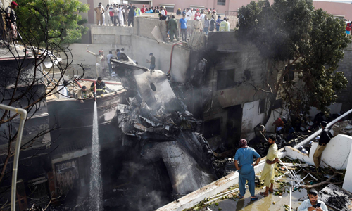 22일(현지시간) 100여명이 탑승한 파키스탄 항공기가 카라치 인근 한 주택가에 추락, 소방관들이 항공기 잔해에 물을 뿌리고 있다. 카라치=AP연합뉴스