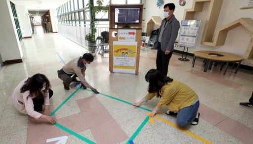 고등학교 2학년과 중학교 3학년, 초등학교 1∼2학년, 유치원생도 27일부터 코로나19 사태 이후 처음으로 학교에 등교한다. 서울의 한 초등학교에서 교직원들이 아이들이 섞이지 않도록 등교 동선을 테이프로 표시하고 있는 모습. 연합뉴스