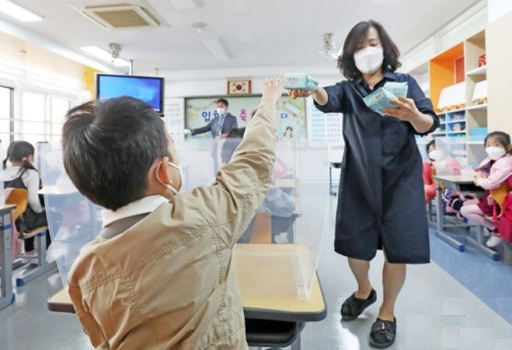 초등학교 1∼2학년생의 등교개학이 이뤄진 27일 경기도 수원시의 한 초등학교에서 1학년 학생들이 코로나19 예방을 위해 마스크를 쓴 채 투명 칸막이를 소독하고 있다. 뉴스1