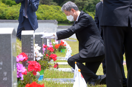 지난달 29일 노재헌 동아시아문화센터 원장이 광주 북구 운정동 국립5·18민주묘지에서 헌화·분향을 한 뒤 묘역 앞에 무릎 꿇고 묘비를 어루만지고 있다. 광주=뉴스1
