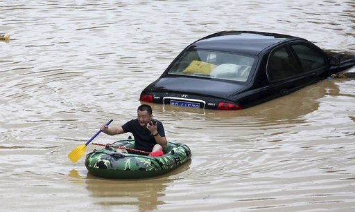 중국에서 한 달 넘게 폭우가 계속되는 가운데 홍수가 발생한 남부 광시좡족자치구 롱슈이 먀오족자치현에서 지난 11일 한 주민이 고무보트를 타고 물에 잠긴 차들 사이를 지나가고 있다. AP연합뉴스
