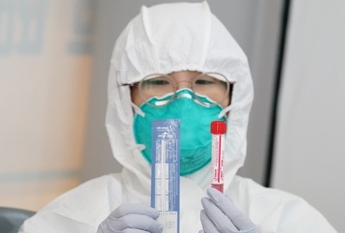 지난 3일 오후 서울 마포구 홍익대에 설치된 마포구 선별진료소에서 방호복을 입은 구 직원이 검사 키트를 들어 보이고 있다. 연합뉴스