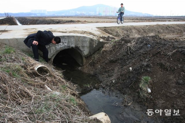경기도 화성시 태안읍 병점동의 들판에서 화성경찰서 강력반직원이 시간이 흐른 뒤를 가정한 한 범인의 몽타주를 들고 현장을 둘러보고있다. 이곳은 영화 ‘살인의 추억’의 배경이기도 하다. 동아일보DB·이훈구 기자 ufo@donga.com