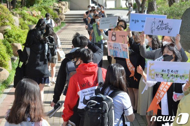 (포항=뉴스1) 최창호 기자 = 신종 코로나바이러스 감염증(코로나19) 여파로 등교가 5차례나 연기되며 80일 만에 등교 수업이 시작된 20일 오전 경북 포항시 남구 영일고등학교 3학년 학생들이 교문 앞에서 선생님들의 응원을 받으며 교실로 걸어가고 있다. 교육부에 따르면 20일 고3을 시작으로 27일 고2·중3·초등1~2·유치원생, 6월 3일에는 고1·중2·초3~4, 6월 8일에는 중1·초5~6학년이 순차적으로 등교를 시작할 예정이다. 2020.5.20/뉴스1