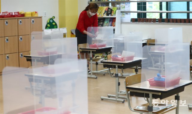 ‘초여름 입학’ 앞둔 1학년 교실 초등 1, 2학년과 유치원생 등의 등교 수업을 하루 앞둔 26일 경기 파주시 와석초등학교 1학년 교실에서 한 교사가 학생을 맞을 준비를 하고 있다. 투명 아크릴판이 설치된 책상마다 마스크와 청소도구 세트가 놓여 있다. 파주=송은석 기자 silverstone@donga.com