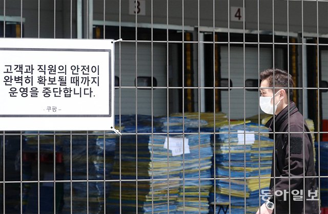 쿠팡發 확산… 하루 56명 추가 확진  27일 오후 신종 코로나바이러스 감염증 집단감염이 발생한 경기 부천의 쿠팡 물류센터가 운영을 중단한 가운데 한 관계자가  걸어가고 있다. 이 물류센터 관련 확진자는 이날까지 69명으로 늘어났다. 부천=송은석 기자 silverstone@donga.com